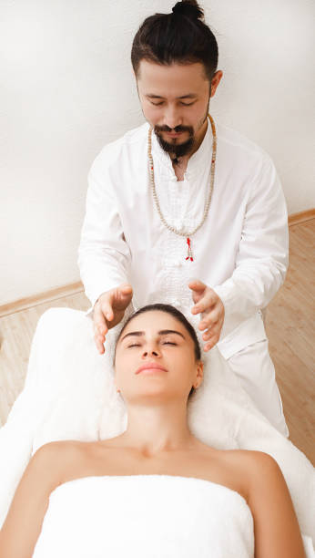 chiropractor faisant le massage énergique de tête. femme obtenant la thérapie de reiki. médecine alternative - reiki alternative therapy massaging women photos et images de collection