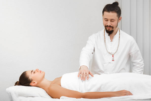 course asiatique de docteur faisant le massage énergique de corps. femme obtenant la thérapie de reiki. médecine alternative - reiki alternative therapy massaging women photos et images de collection