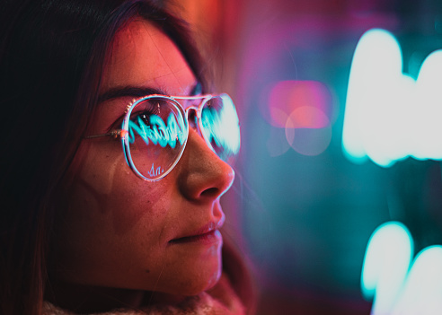 reflection of neon lights on a girl's glasses
