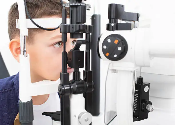 Boy's eyesight test with binocular slit-lamp. Checking retina of a teenager's eye. Ophthalmology Clinic