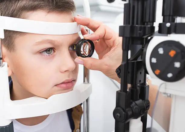 Boy's eyesight test with binocular slit-lamp. Checking retina of a teenager's eye close-up. Ophthalmology Clinic