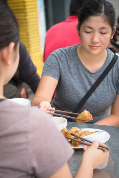 istock POV, Multi-Ethnic Sisters Sharing Plate of Spring Rolls, Hanoi, Vietnam 1206607928