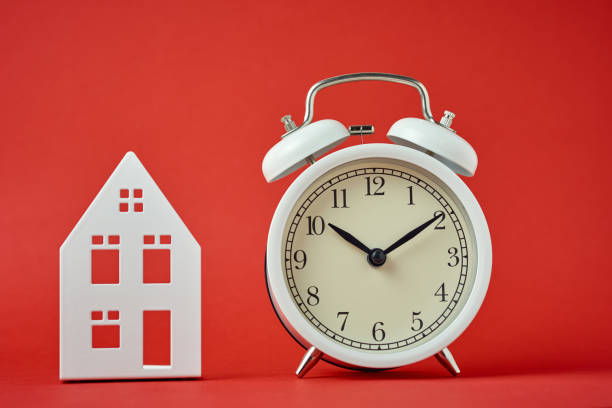 istock White retro alarm clock and miniature house on the red backgroumd 1206608015