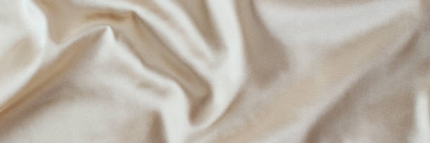 istock Golden light silk background with a folds.  Abstract texture of rippled satin surface, long banner 1206609382