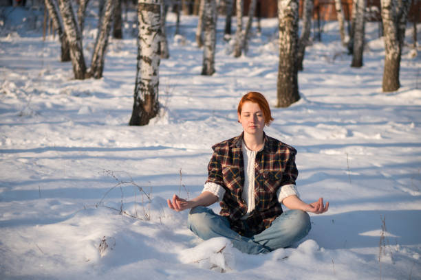 istock Cute ginger girl meditates in winter forest. 1206609573