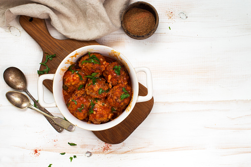 Meatballs in tomato sauce close up on a white wooden background. Flat lay. Copy space