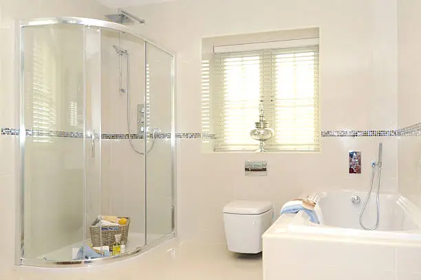 a quality bathroom including shower and enclosure, toilet and bath, with white tile decoration