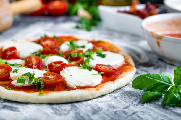 Prepering margherita pizza with mozzarella for baking stock photo