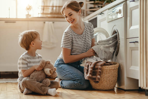 szczęśliwa matka rodzinna gospodyni domowa i dziecko w pralni z pralką - stereotypical housewife little girls family domestic kitchen zdjęcia i obrazy z banku zdjęć