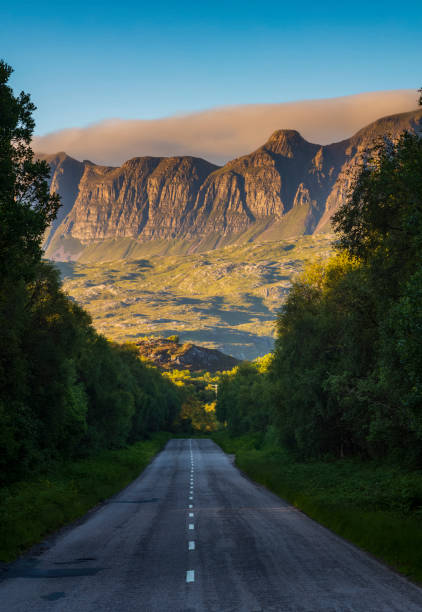 die bergkette des knockan crag national nature reserve bei sonnenuntergang, von der zweispurigen autobahn der a385 bei elphin, lairg, schottland. - empty nobody two lane highway highway stock-fotos und bilder