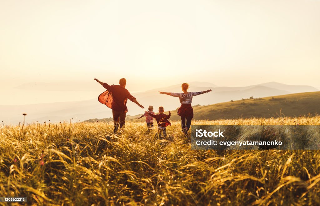 幸福的家庭：母親、父親、孩子、兒子和女兒在夕陽下奔跑和跳躍 - 免版稅家庭圖庫照片