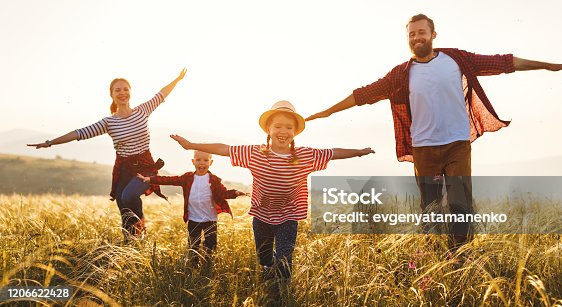 istock Happy family: mother, father, children son and daughter runing and jumping on sunset 1206622428