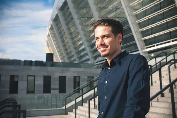 Photo of Successful caucasian businessman stand on stairs in modern city.