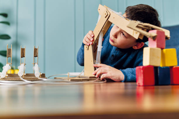 6-7 jahre altes kind erfand einen roboterarm mit pappe und spritze. roboter ist seine hausarbeit. er ist ein erfolgreicher schüler in der grundschule. - 6 7 years fotos stock-fotos und bilder