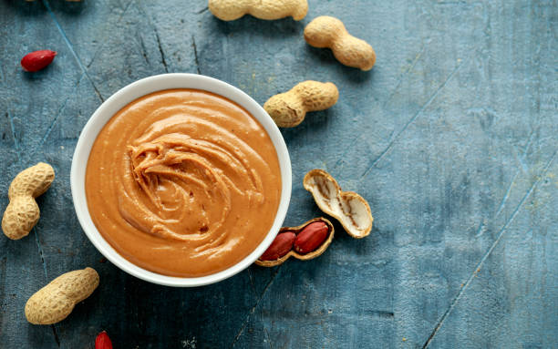 istock Smooth Peanut Butter in white bowl with nuts 1206629076