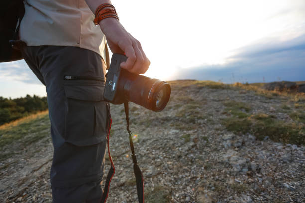 istock Man in mountains holds reflex camera during sunrise 1206631481
