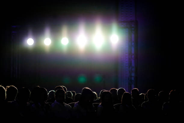 istock Silhouettes of people under bright background lights 1206632545
