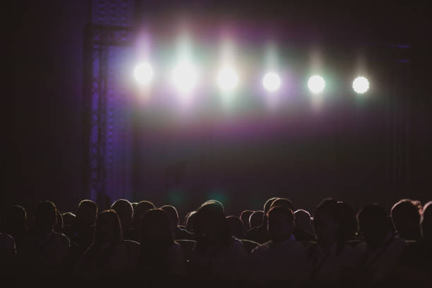 istock Silhouettes of people under bright background lights 1206632546