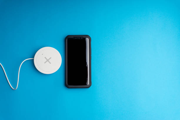 istock Smartphone charging on a charging pad or dock on blue background. 1206634063