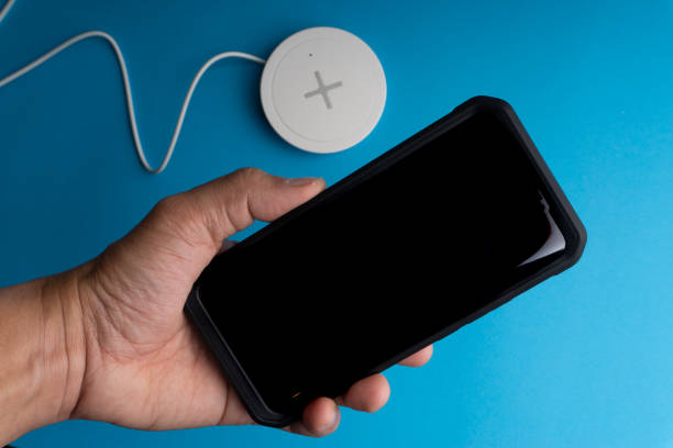 istock Smartphone charging on a charging pad or dock on blue background. 1206634994