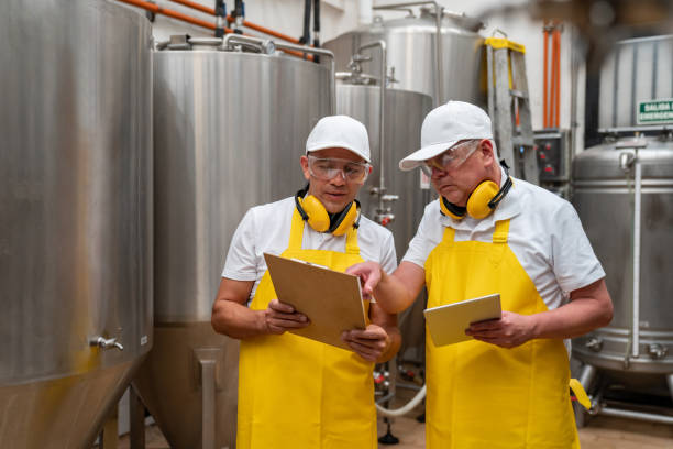 istock Workers talking at a brewery factory and looking at documents on a clipboard 1206641710