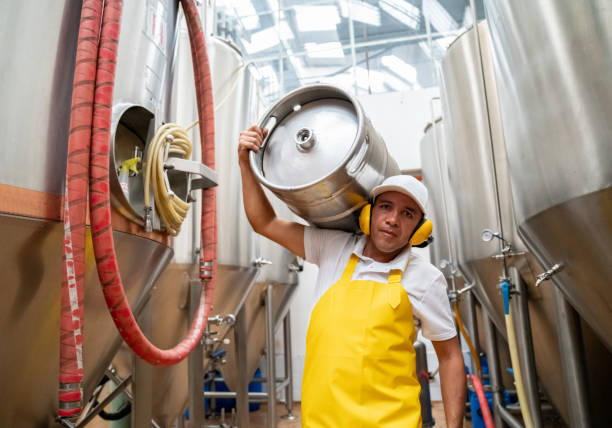 Operator carrying beer barrels at a brewery factory - industrial concepts