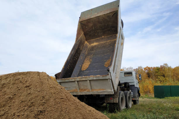 A dump truck unloads sand at a construction site to mix cement. A dump truck unloads sand at a construction site to mix cement.2020 topsoil stock pictures, royalty-free photos & images