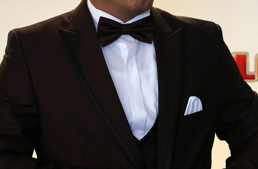 Portrait of young man wearing black elegant suit looking away. Studio shot, white background.
