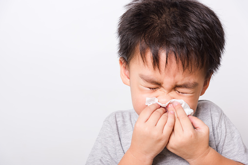 Closeup Asian face, Little children boy cleaning nose with tissue on white background with copy space, health medical care