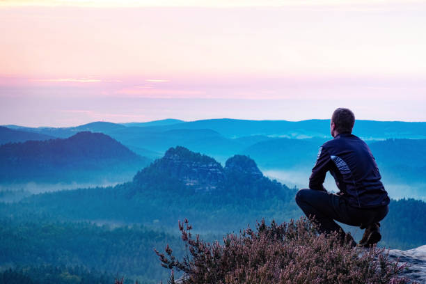 istock Calm man sitting on top of mountain enjoying view 1206649967