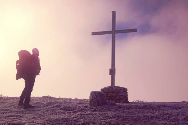 istock Hiker reaches summit of mountain with cross 1206651843