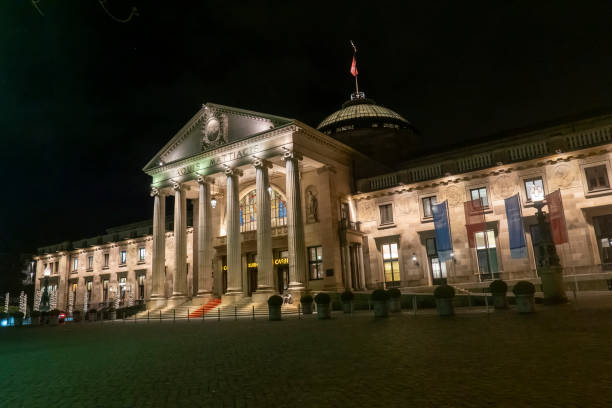 the Wiesbaden casino with famous entrance with roman pillars by night Wiesbaden, Germany - January 31, 2020:   the Wiesbaden casino with famous entrance with roman pillars by night. kurhaus casino stock pictures, royalty-free photos & images