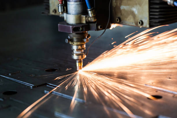 istock laser cutting process with a sheaf of sparks and motion blur of head unit while piercing through zinc plated steel sheet 1206656946