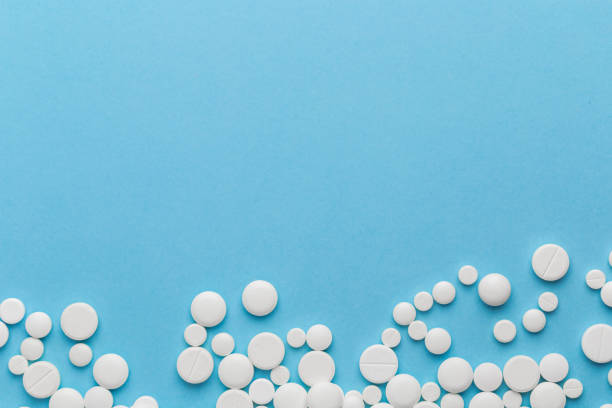 istock scattered white pills on a blue table. Layout for special offers such as advertising or other ideas. The concept of medicine, pharmacy and healthcare. Space for copy. 1206657775