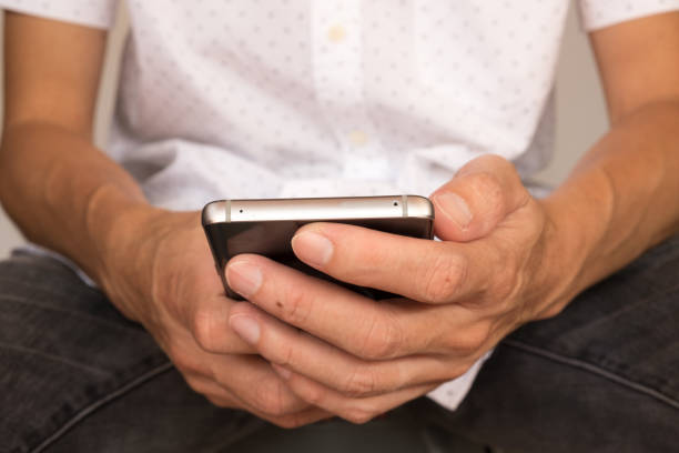 istock a man is sitting on chair and use smart phone with his hands 1206658948