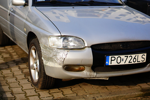 Poznan, Poland - February 15, 2020: Close up of a parked old damaged Ford Mondeo car with Polish license plate on a parking place. Vehicle is fixed with tape.