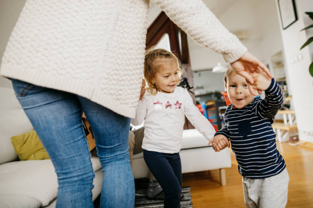 Young family dancing together Two little kids and their mother are dancing in a living room. They are casually dressed and it is daytime. baby boy dancing with his mommy stock pictures, royalty-free photos & images