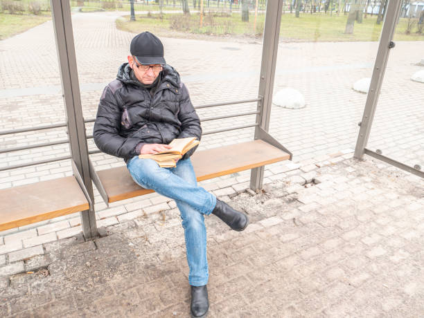 istock A man with glasses is reading a book on a bench. 1206661813