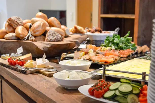 A breakfast buffet with rolls, cheese and several vegetables