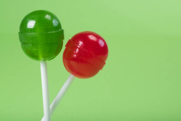 Two lollipops on a stick, a close-up at the green background.