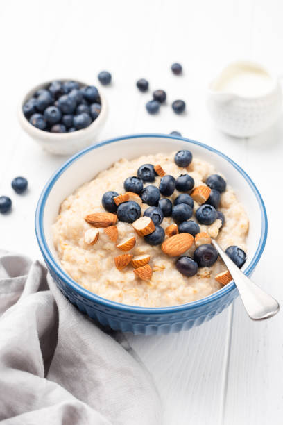 bowl of porridge oats with blueberries, almonds - quinoa spoon wood photography imagens e fotografias de stock