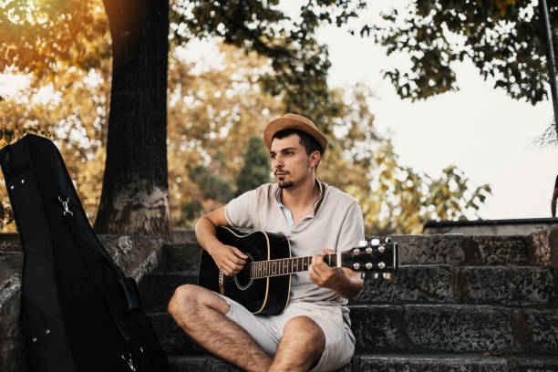 istock Handsome musician playing acoustic guitar in park 1206678408