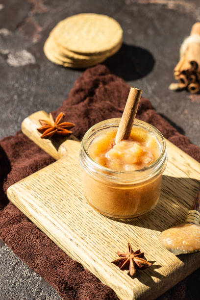 istock Spicy pear jam in glass jar, crackers, spices (cinnamon and anise) and thyme. Brown stone background. Rustic style. 1206680032
