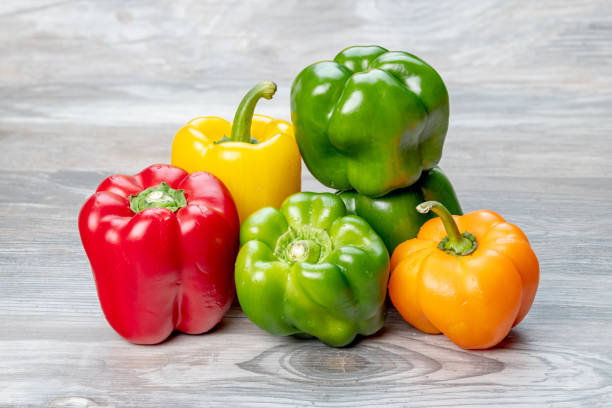 istock Green orange and red bell peppers on a wood tabletop 1206682498