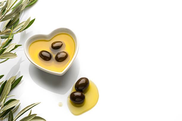Extra virgin olive oil surrounded by freshly harvested olives