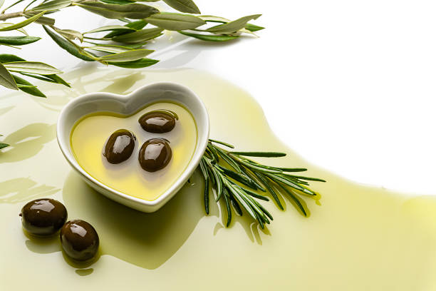 Glass jug with olive oil and scattered olives on black mirror background, low key photo