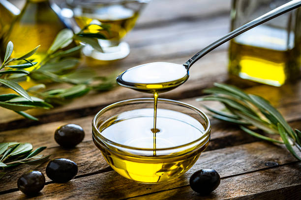 pouring extra virgin olive oil in a glass bowl - virgin olive oil imagens e fotografias de stock