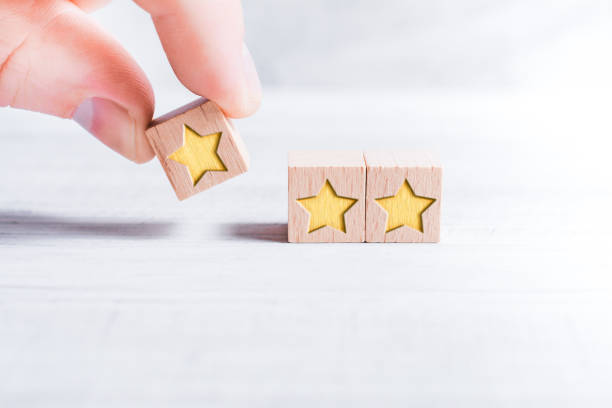 3 Star Ranking Formed By Wooden Blocks And Arranged By A Male Finger On A White Table stock photo