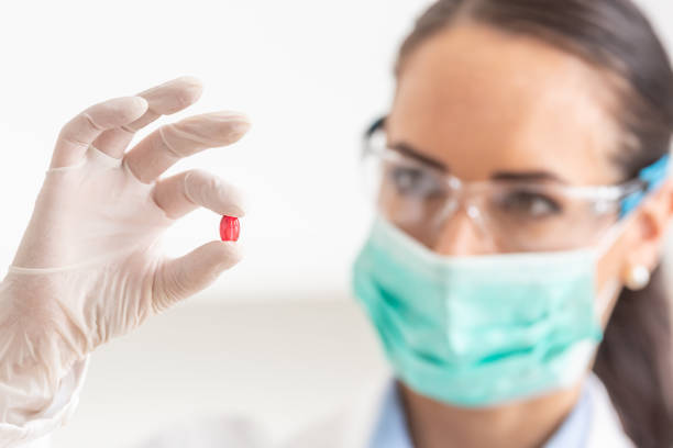 istock Young female scientist holding a red pill - close-up. 1206687606