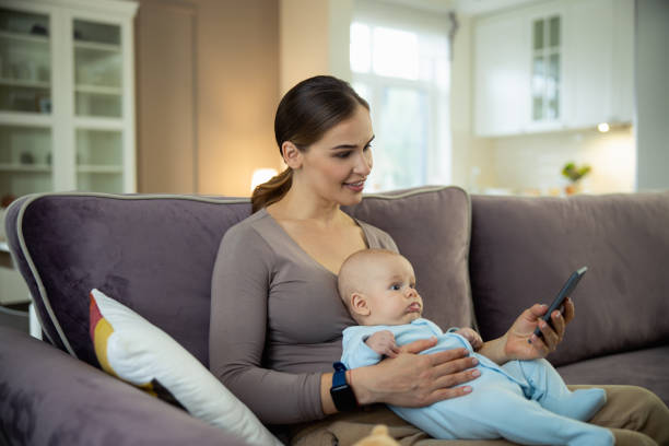 istock Smiling young mother sitting with kid and using mobile phone 1206692743